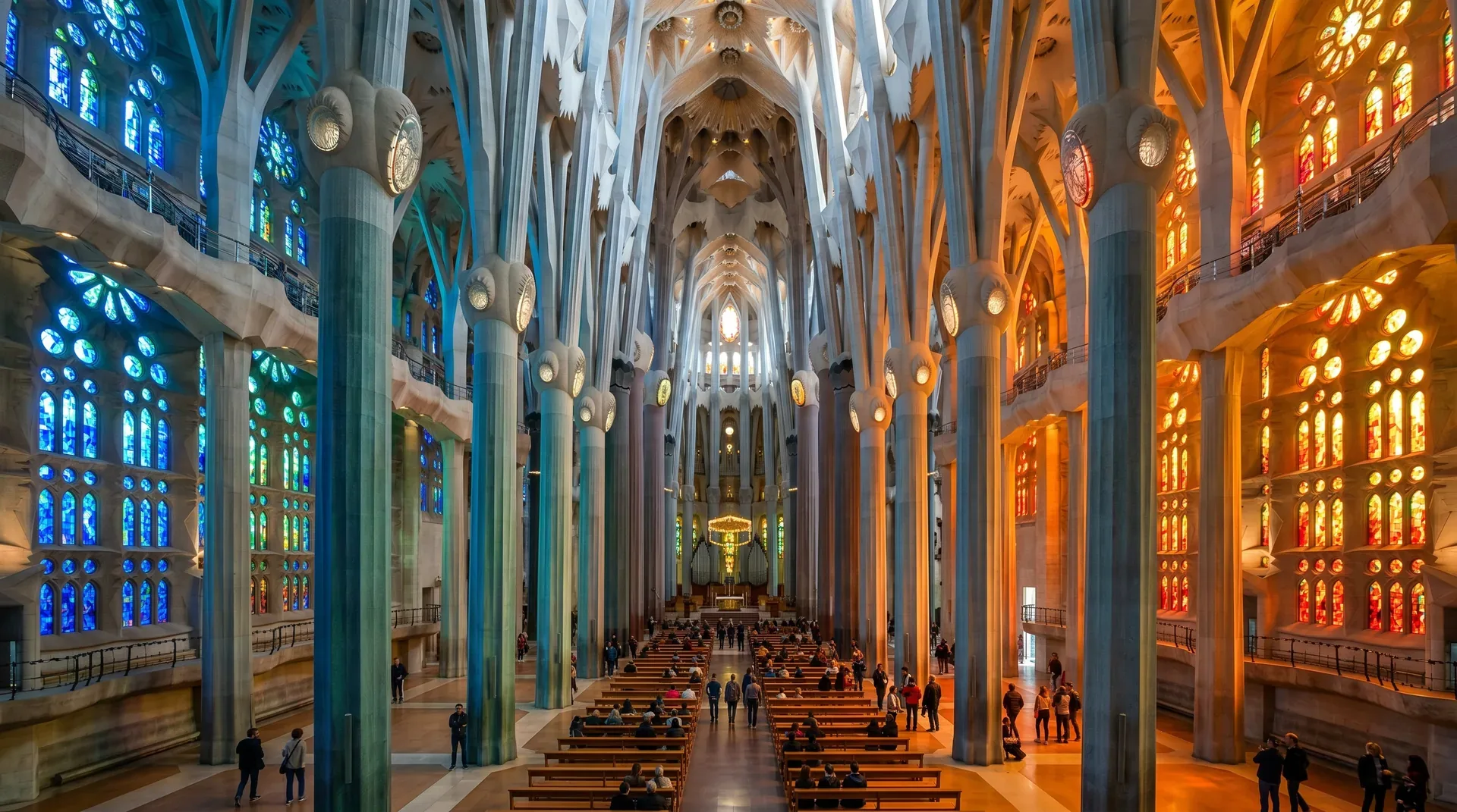 The Sagrada Família nave with coloured stained glass light creating the symbolic colour journey from blue-green to red-amber